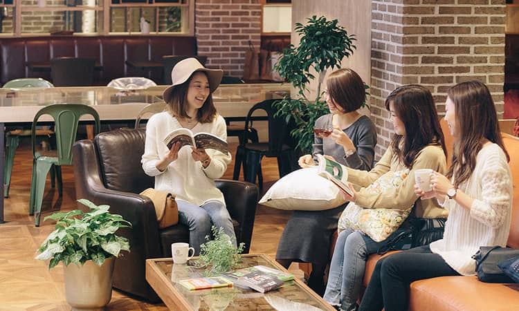 ラウンジで本を片手に会話する４人の女性